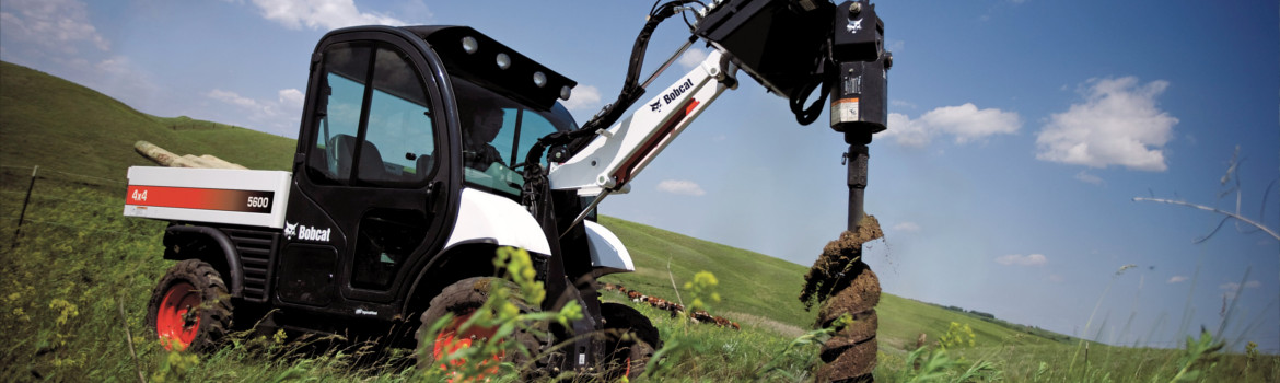 Bobcat® Auger attached to a Bobcat UTV drilling hole into ground in hilly field on sunny day